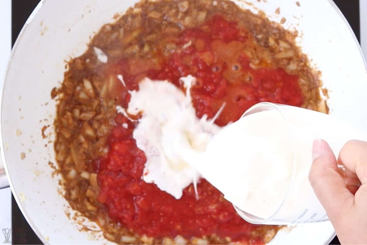 adding tomatoes and cream to pan