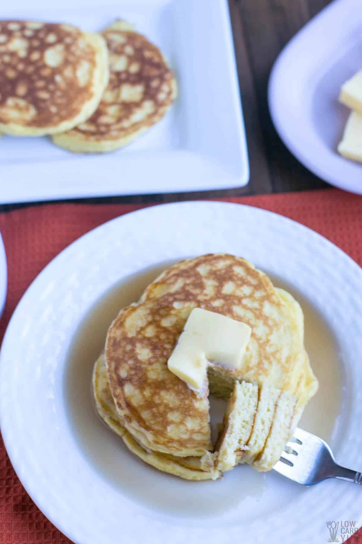 keto coconut flour pancakes on white plate with fork bite
